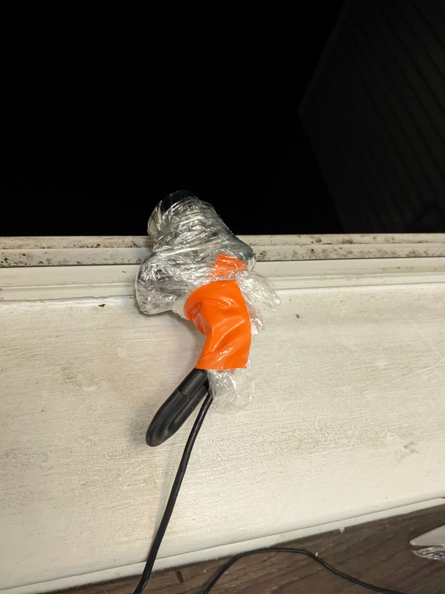 Picture of the webcam completely wrapped in plastic wrap secured by orange
duct tape sitting on my window sill